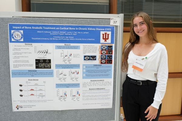 Allison Kolhouse, a student from Columbus North High School, stands with her poster at the symposium.