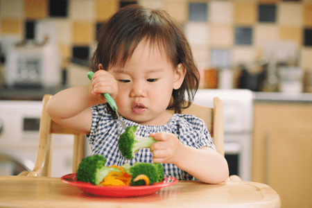 Young child eating a plate of vegetables