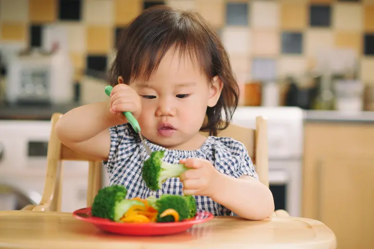 Young child eating a plate of vegetables