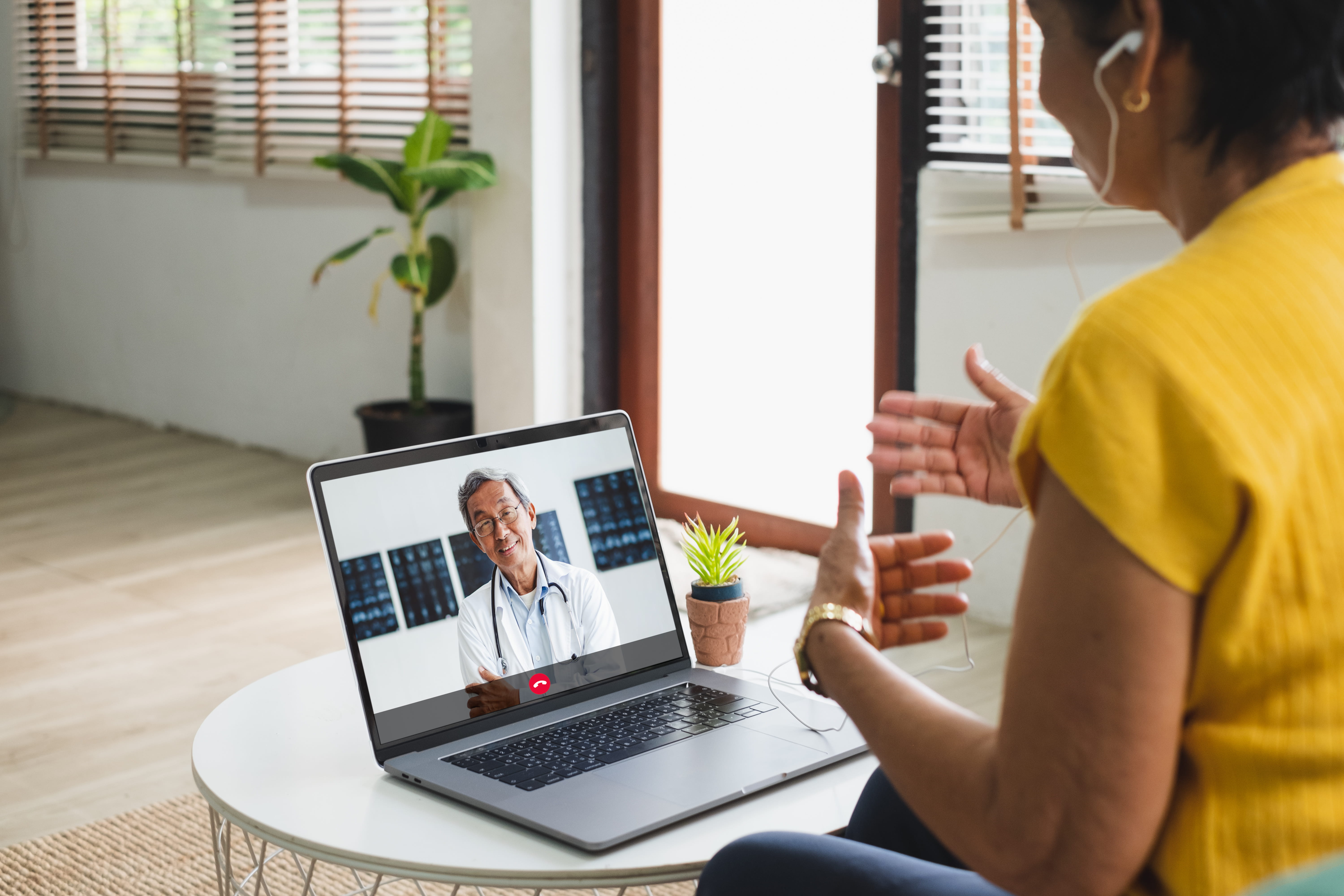 A woman speaks to a doctor on a laptop.