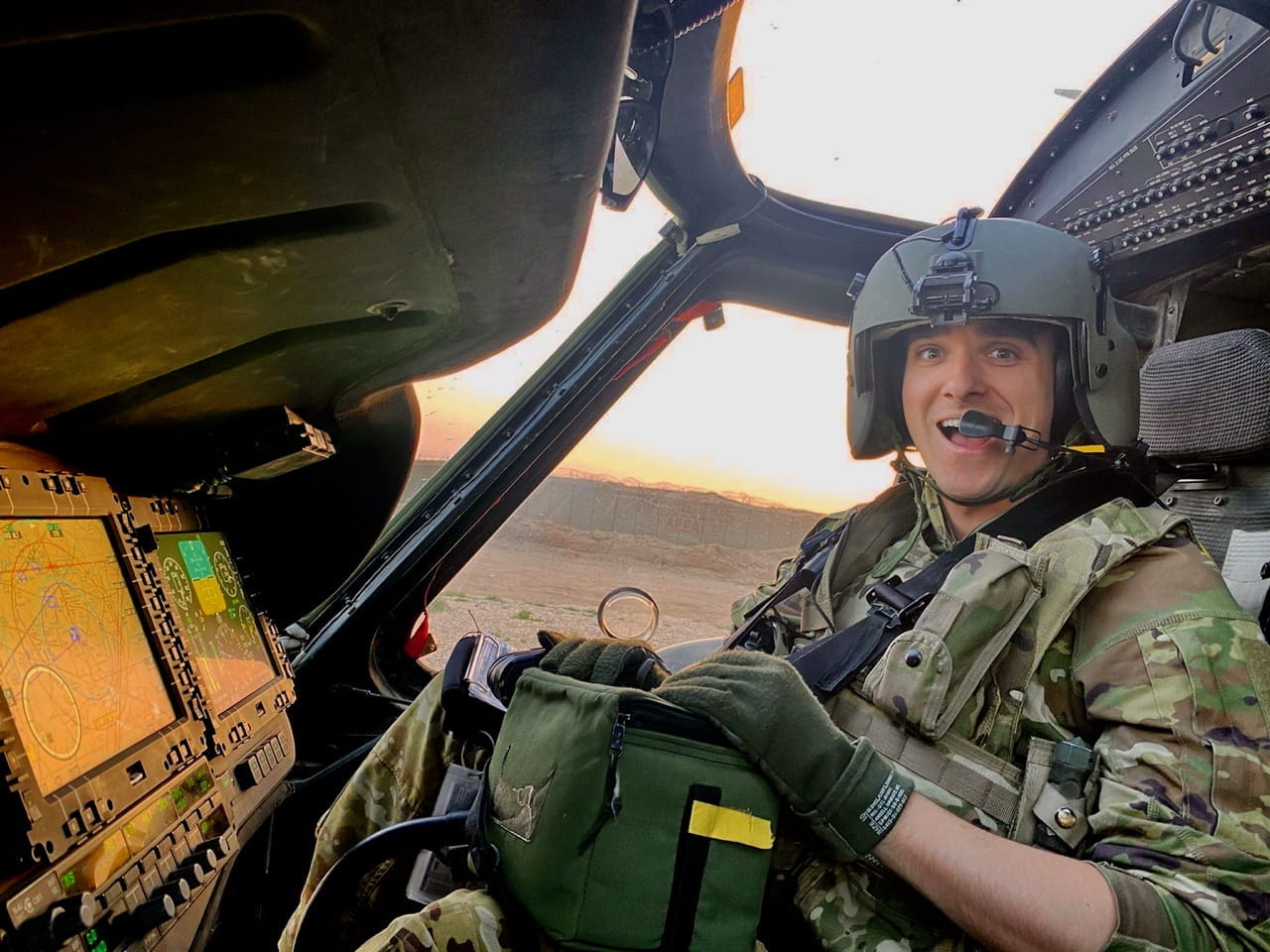 Oliver Strobel in military fatigues at the controls of a helicopter at daybreak