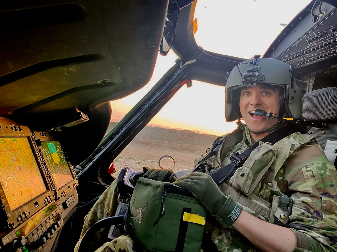 Oliver Strobel in military fatigues at the controls of a helicopter at daybreak
