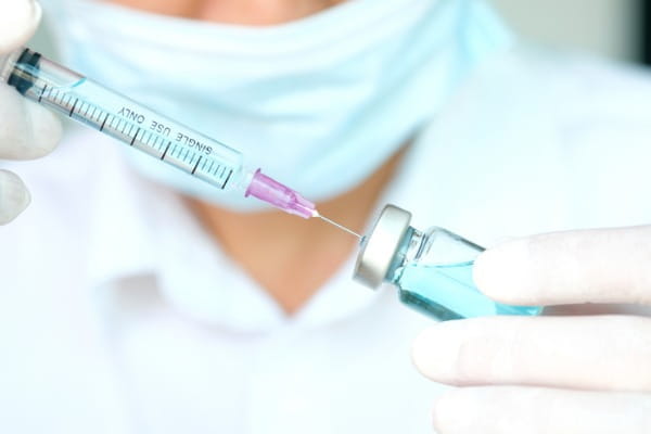 The hand of doctor holding syringe and medicine bottle, preparing an injection.