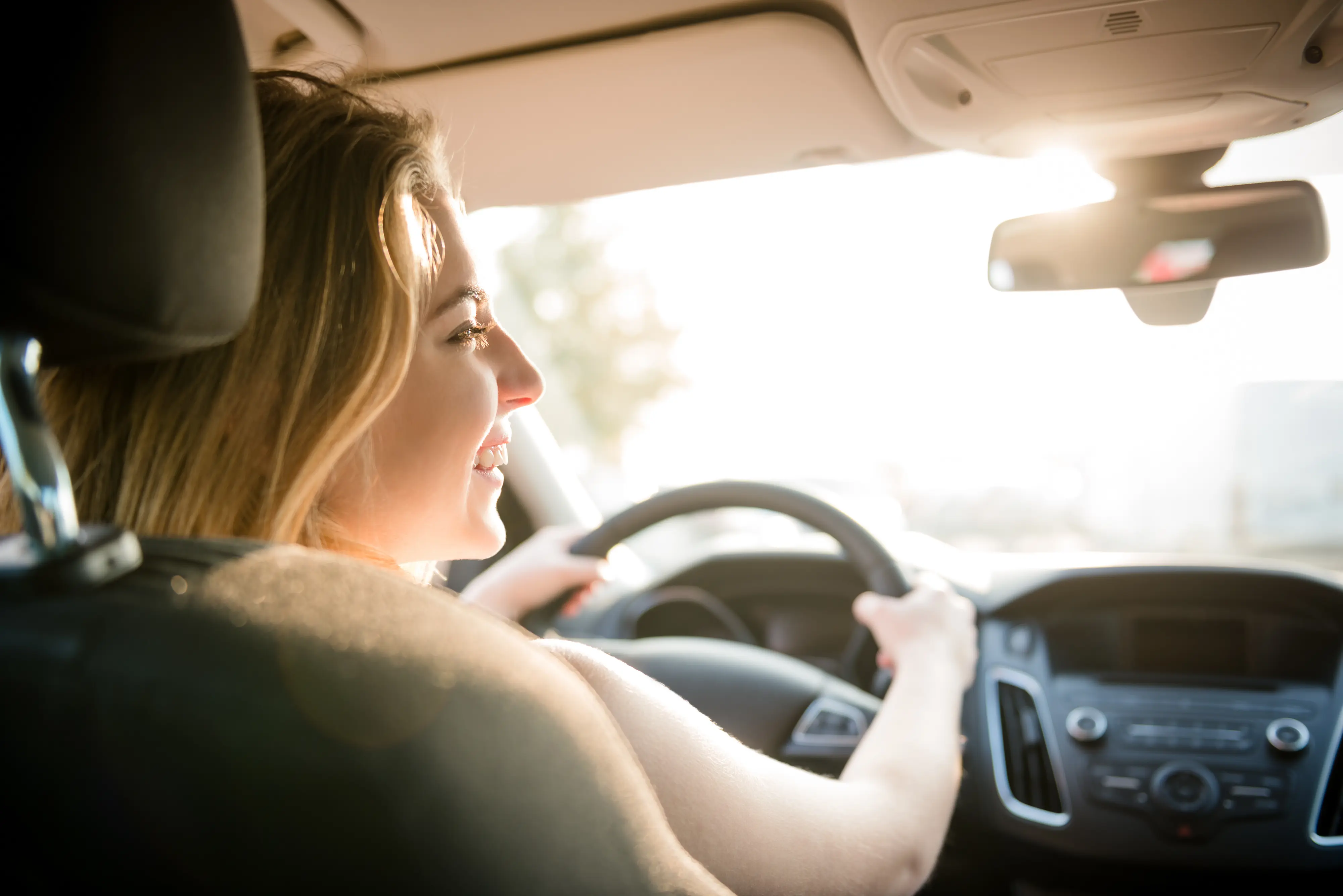 Woman with both hands on steering wheel driving 