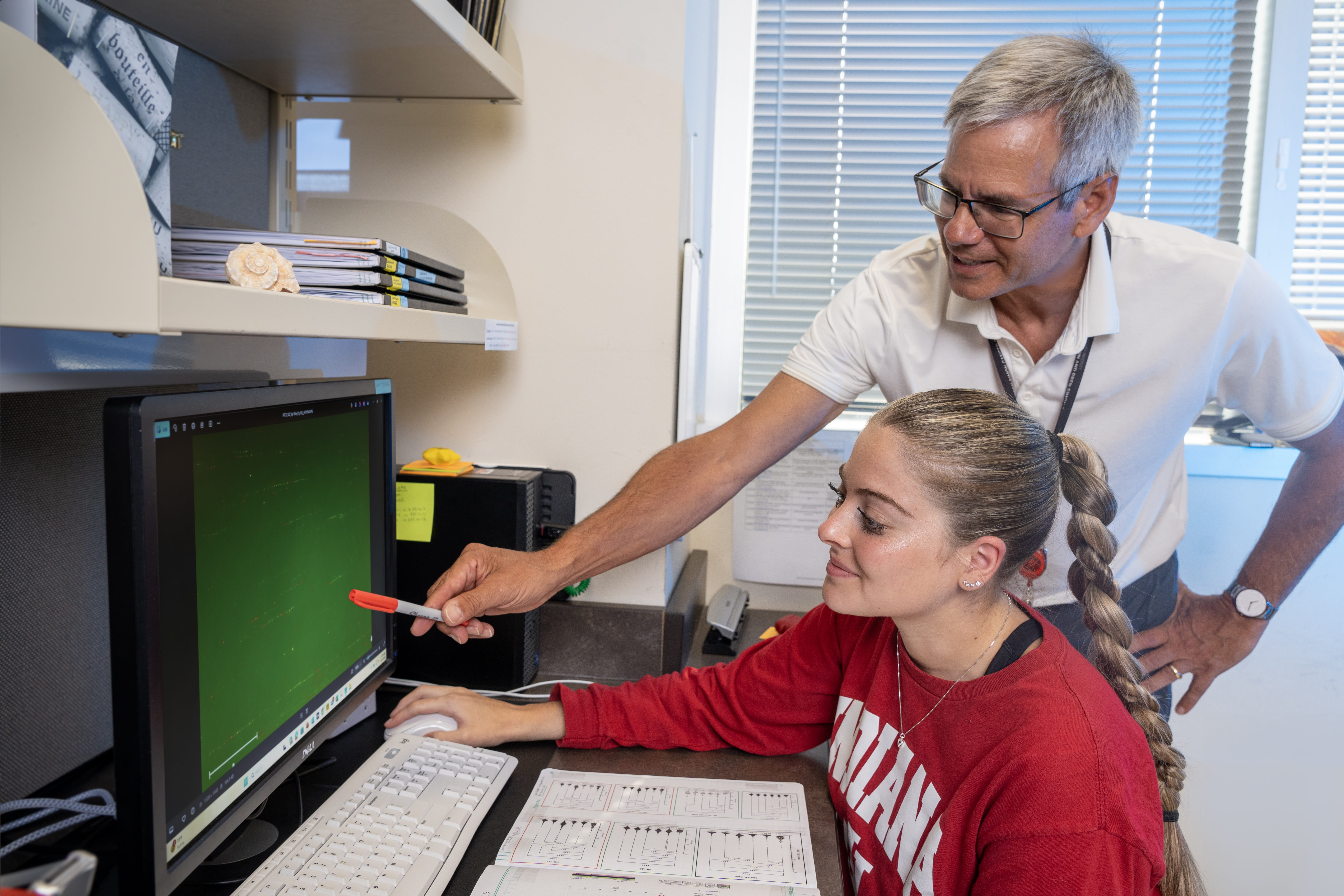 Professor John Turchi and student examining equipment in the lab setting.