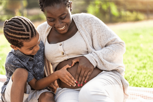 Mother and son touching pregnant belly doing heart shape with hands