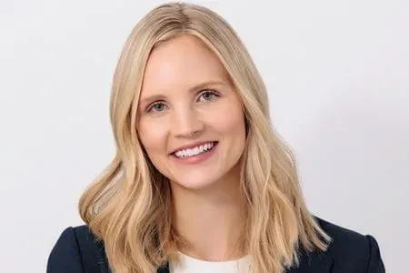 Headshot of Laura Vater, blonde woman in dark blazer on white background, smiling