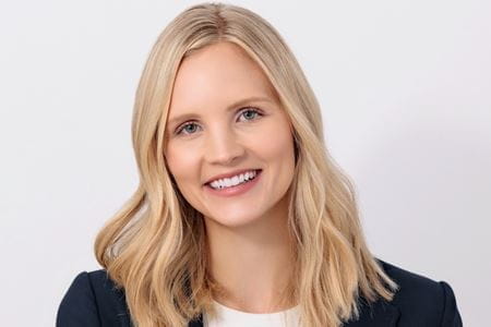 Headshot of Laura Vater, blonde woman in dark blazer on white background, smiling