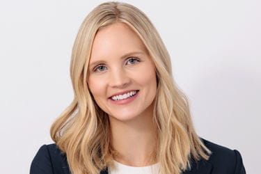 Headshot of Laura Vater, blonde woman in dark blazer on white background, smiling