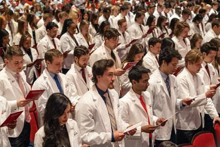 MD students in the Class of 2027 in their white coats, standing and reciting the Physician's Oath