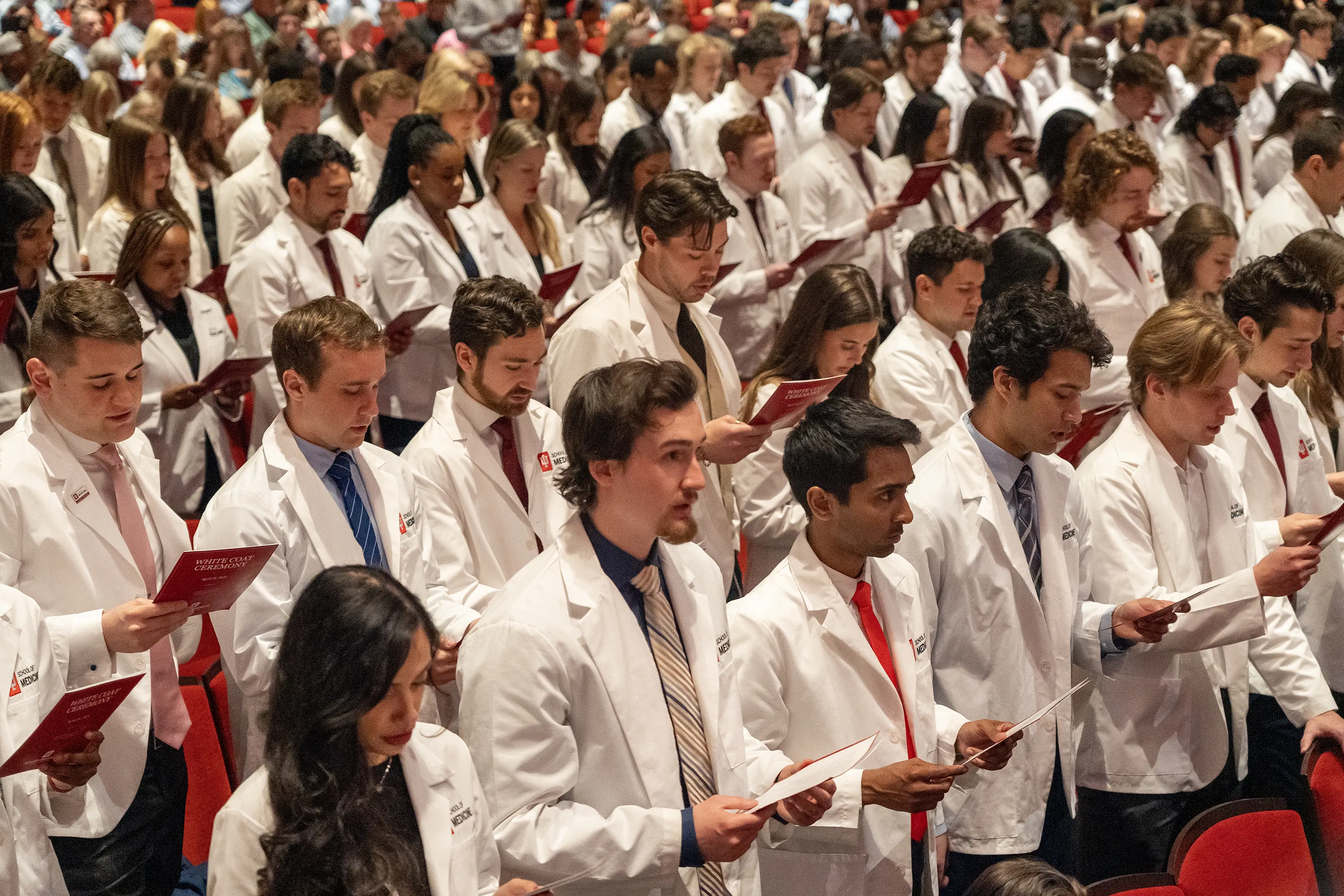 MD students in the Class of 2027 in their white coats, standing and reciting the Physician's Oath