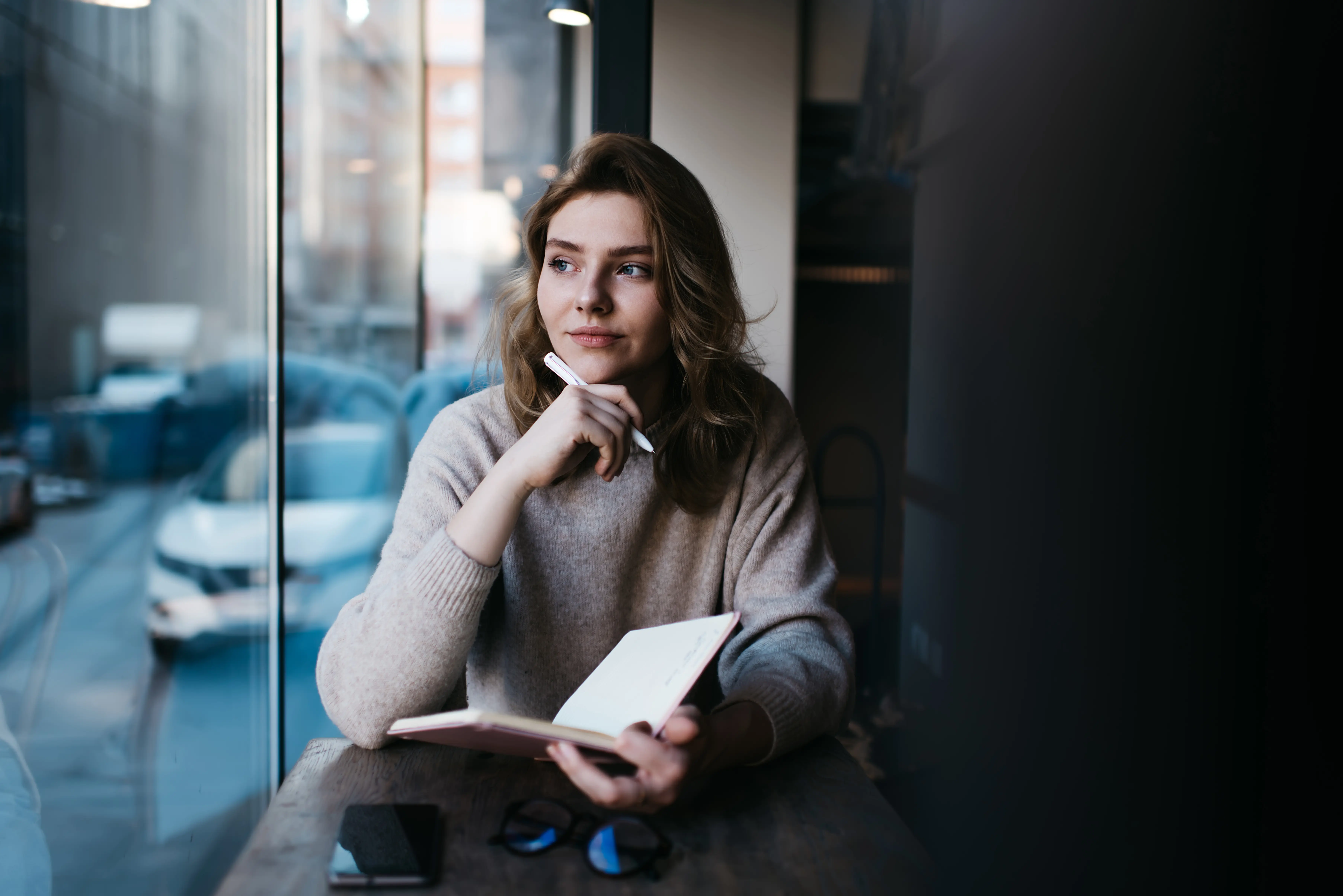 Pensive woman thinking about ideas with notebook at table 