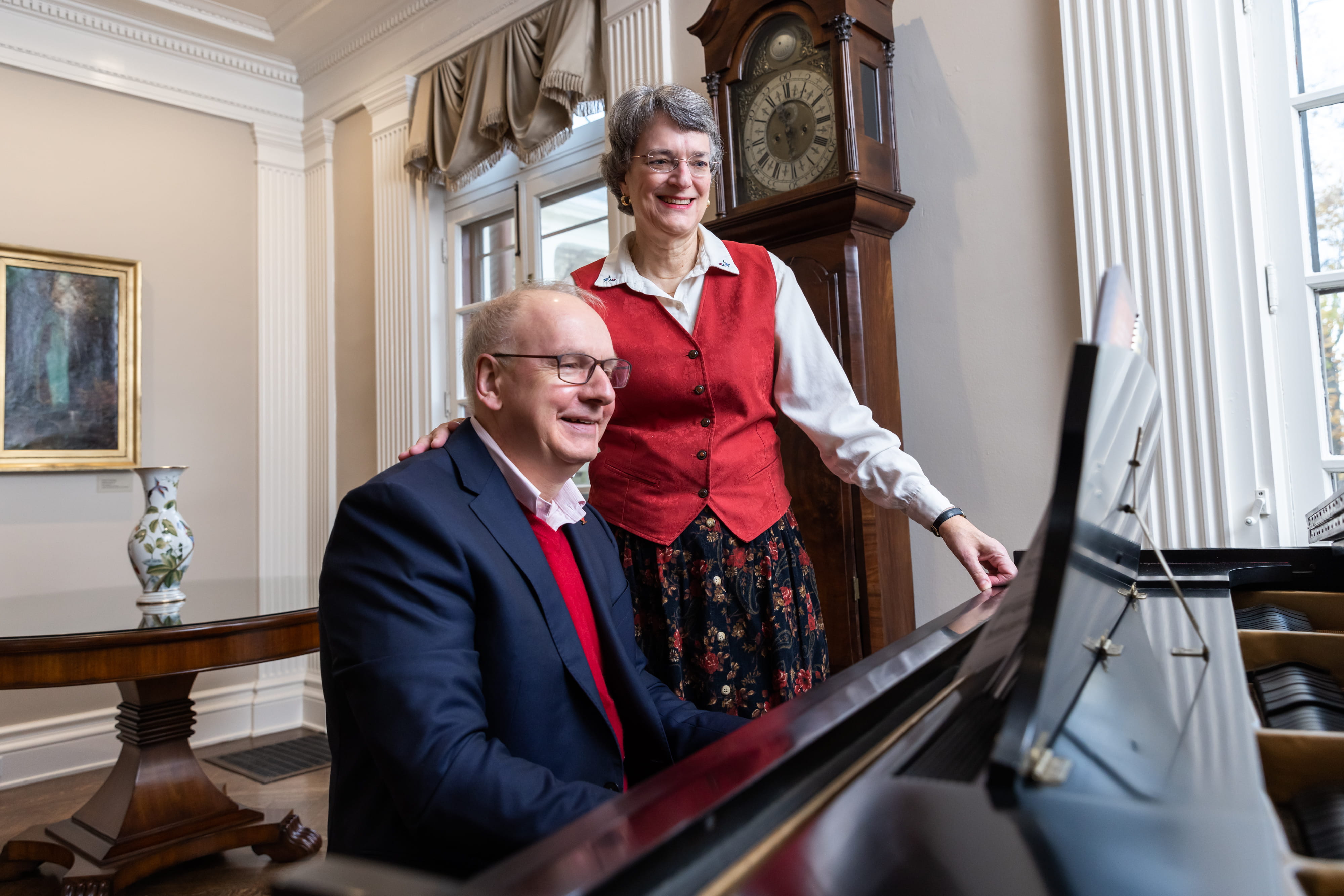 Jay sits at a piano with wife Robin at his side