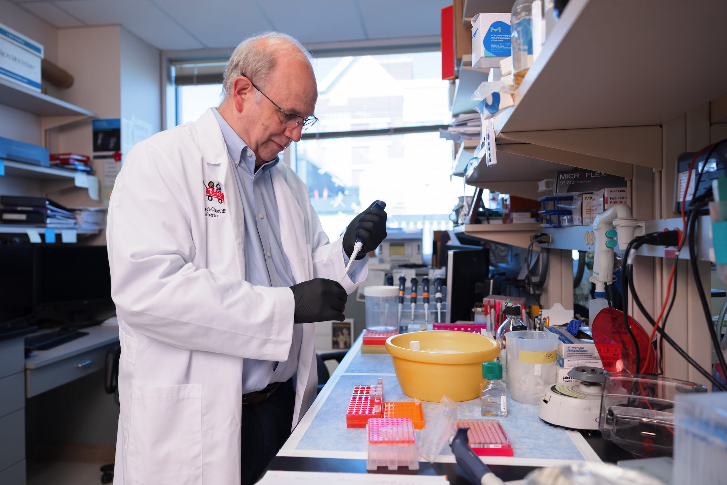 Wade Clapp works in his lab wearing a white coat and using a pipette