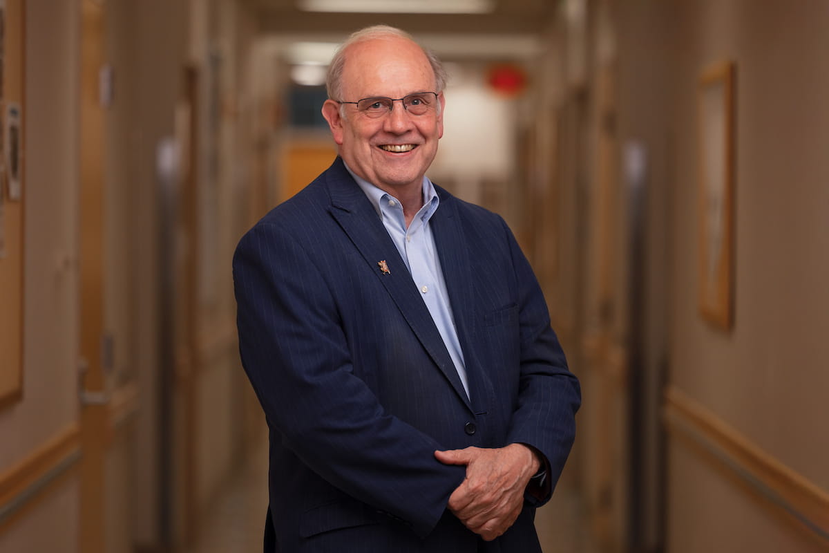 Wade Clapp poses in a hallway at the cancer center, wearing a navy suit