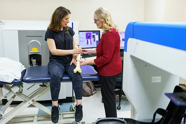 Melissa Kacena holds a bone model up to the arm of a research study participant at the Indiana Center for Musculoskeletal Health.
