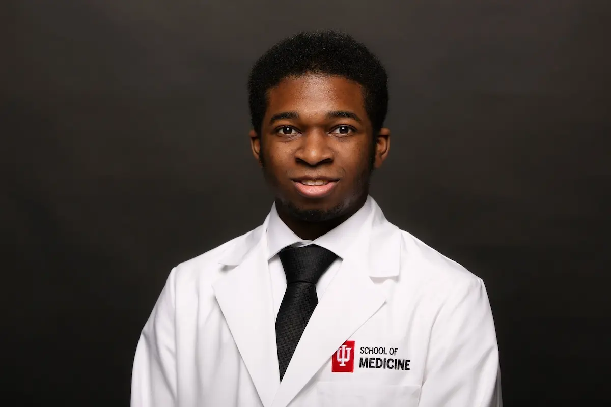 Head-and-shoulders portrait of Matthew Blango, a young Black man wearing a white shirt and black tie with an IU School of Medicine logo white coat