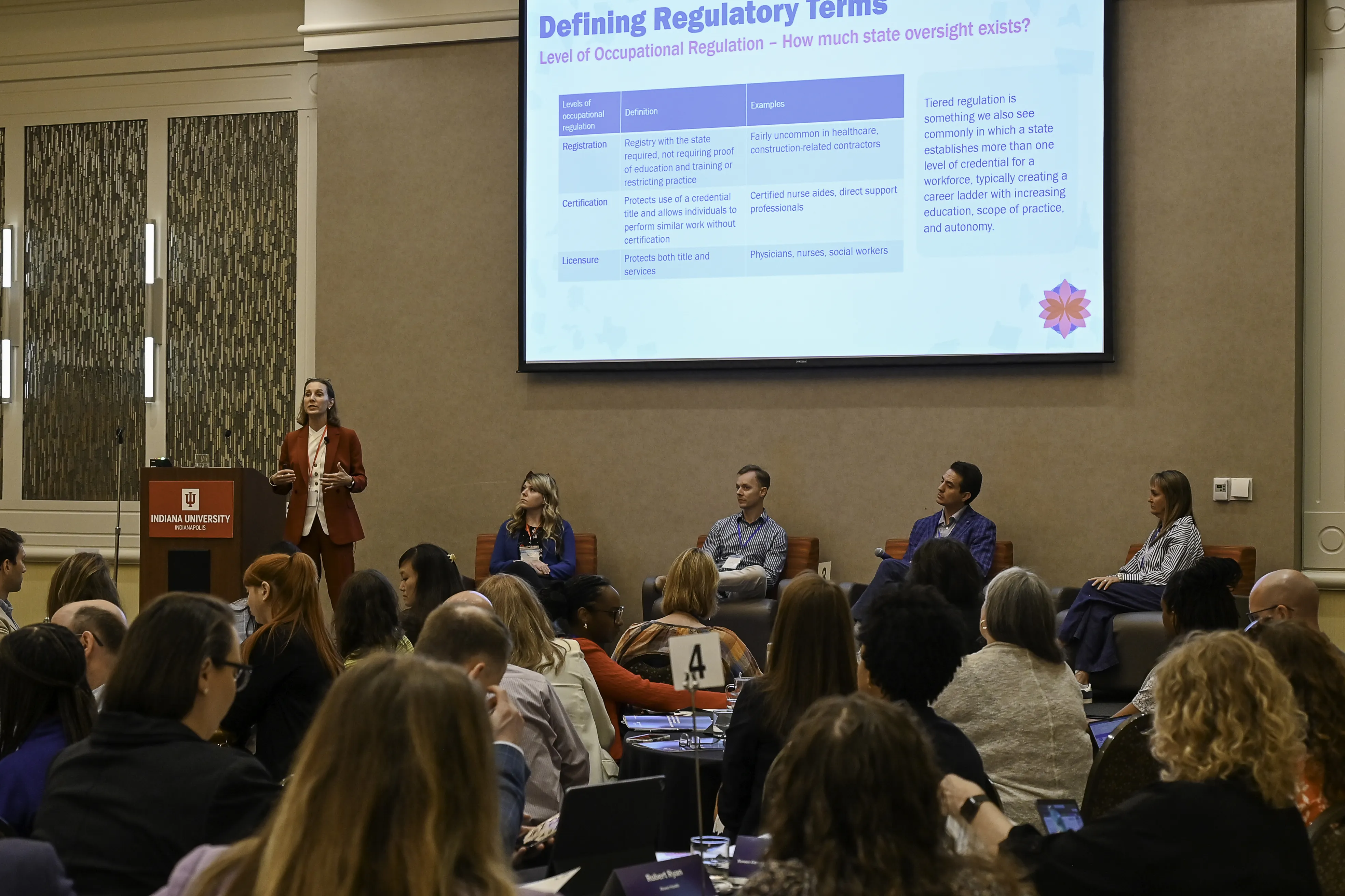 A woman at a podium presents to a group of people