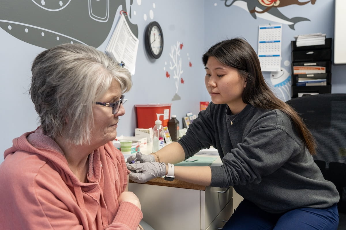 Lucia Li gives an older woman a vaccine in the clinic