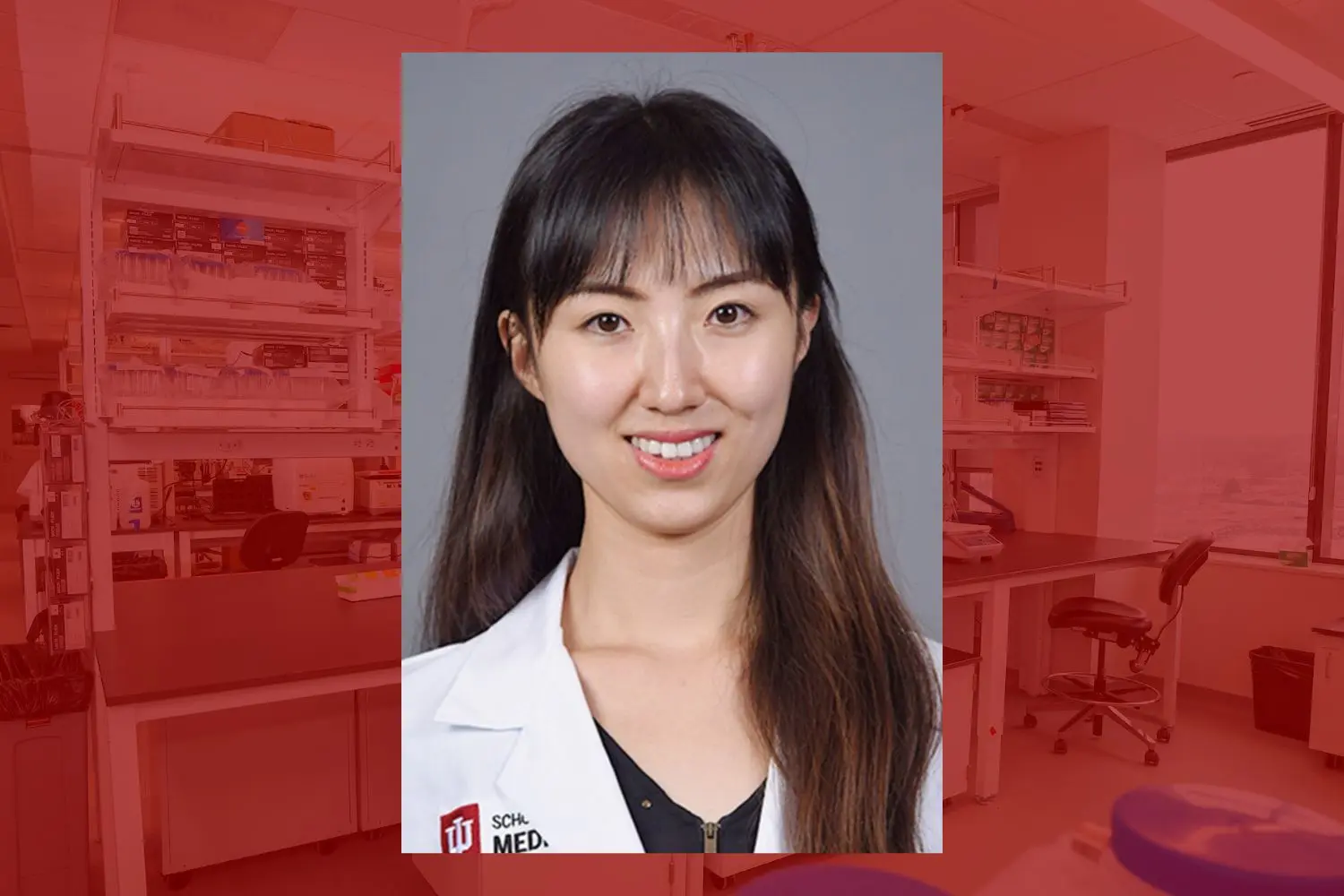 A woman with brown hair and brown eyes smiling wearing a lab coat. 