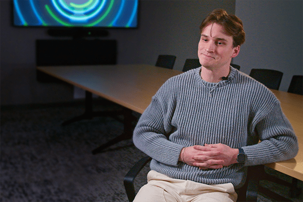 IU medical student Graham Keele sits in a gray sweater in front of a TV display.
