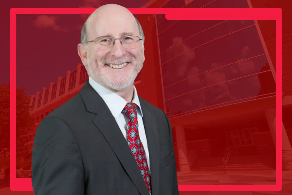 Greg Sachs, MD, is picture against a plain red background.