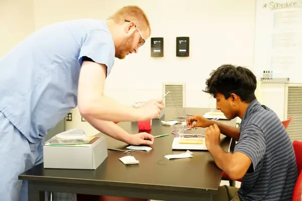 Surgery resident guides a SOQIC intern through a suturing exercise. | Photo courtesy Cassie Needy