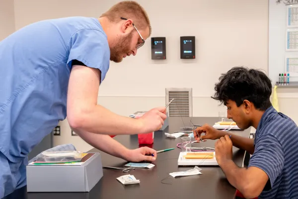 Surgery resident guides a SOQIC intern through a suturing exercise. | Photo courtesy Cassie Needy