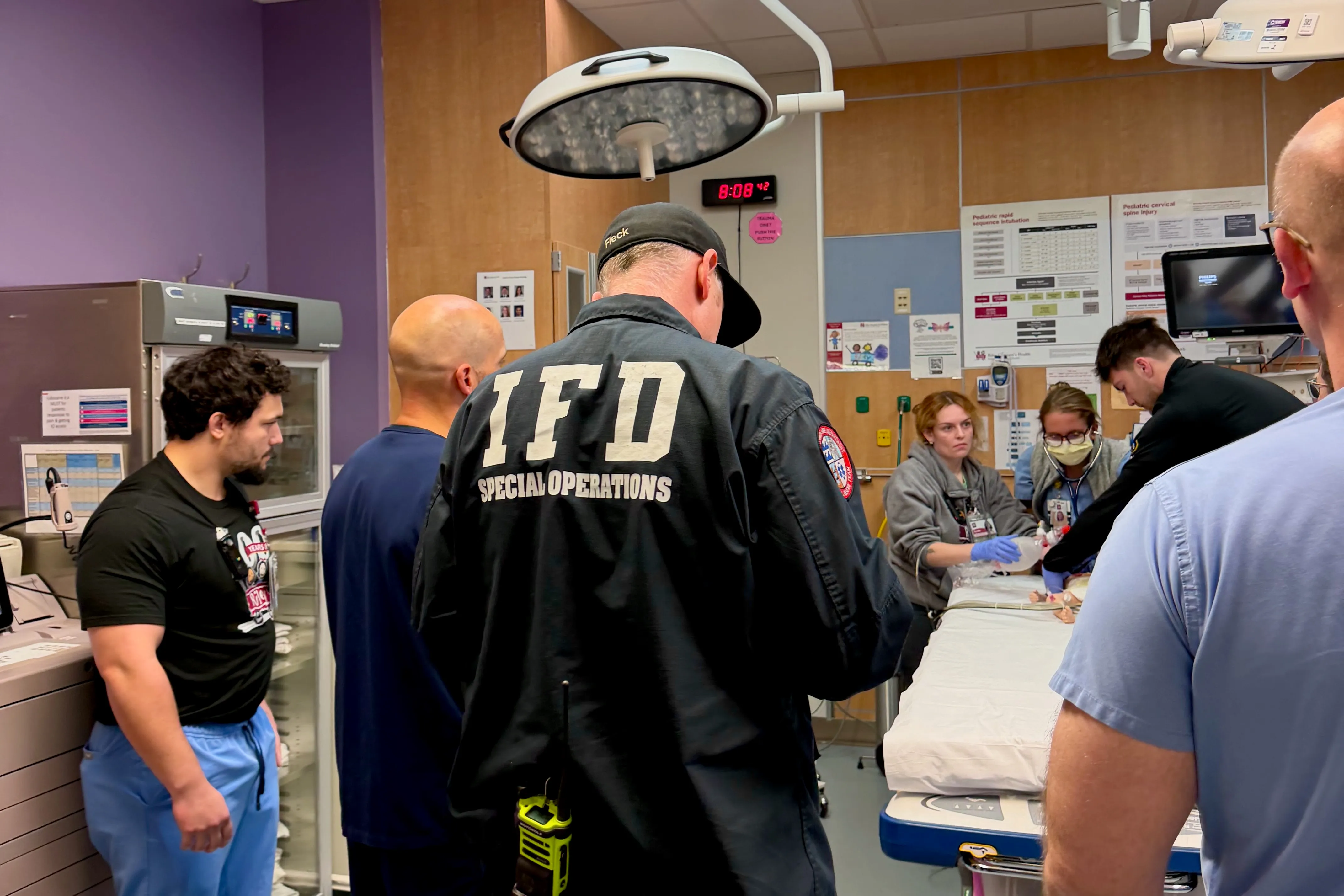 Hospital workers and emergency personnel are assembled around a bedside in the trauma bay at Riley Hospital during a simulation.