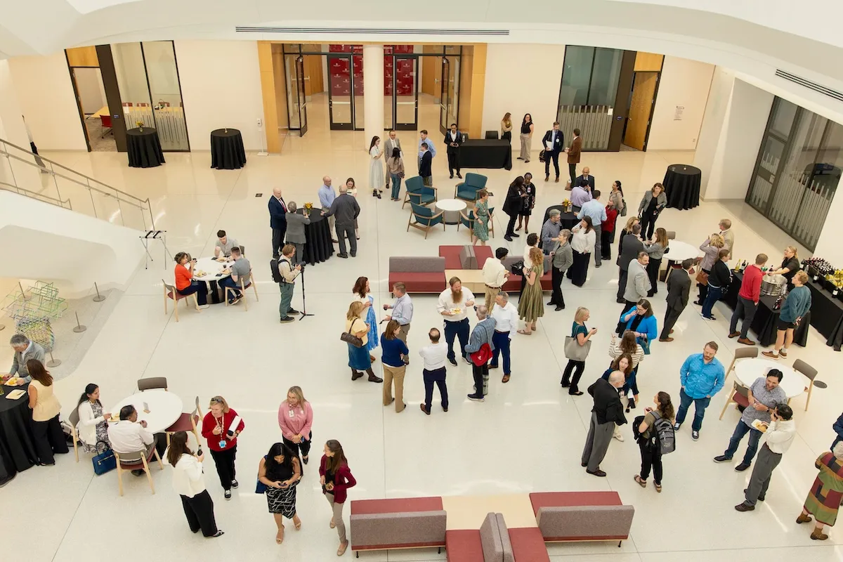 View of the atrium filled with people mingling below, taken from the second floor of the Medical Education and Research Building. 