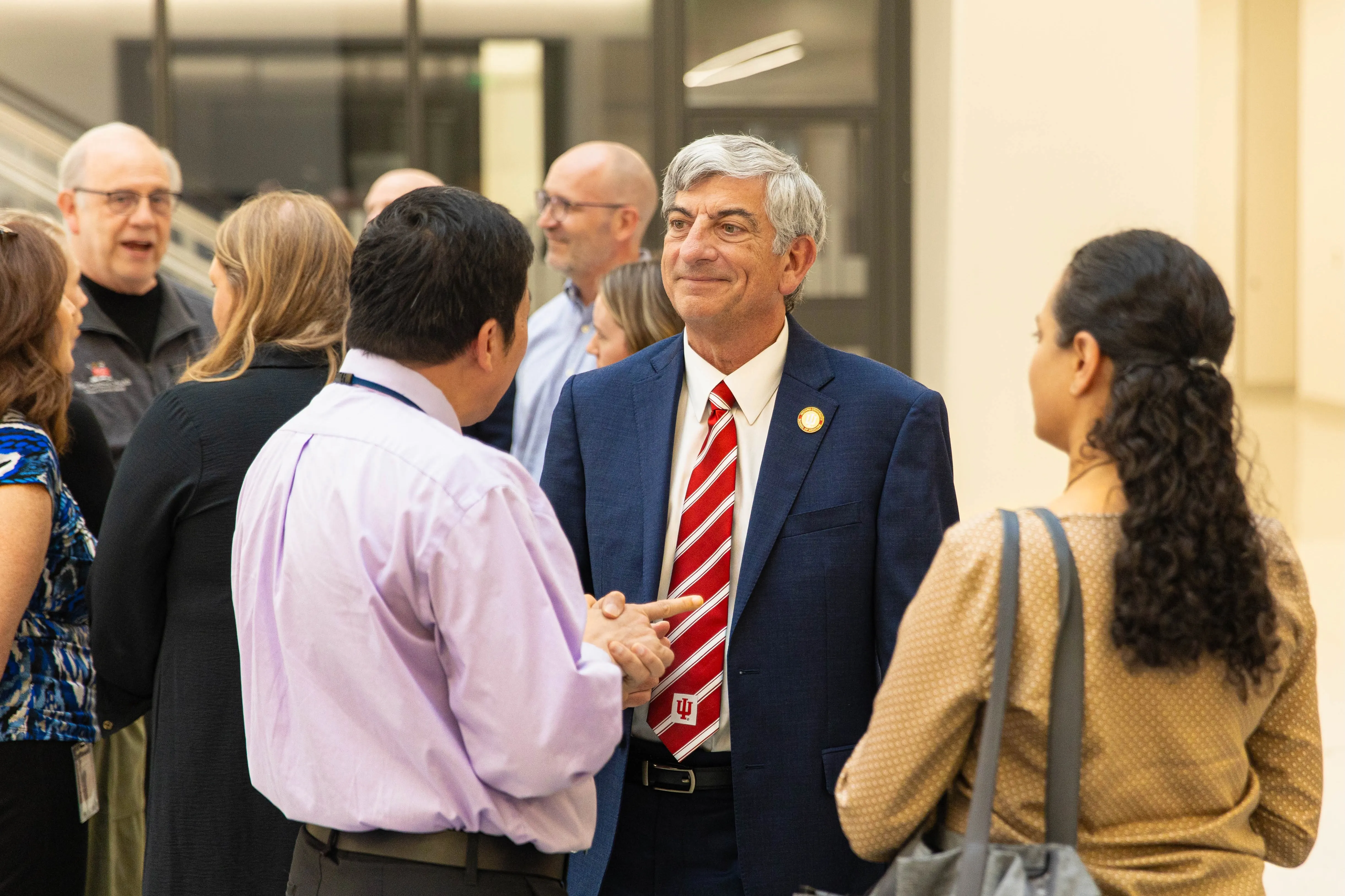 Dean Scott Boden, in suit and red IU tie, mingles with two faculty members in the Medical Education and Research Building atrium.