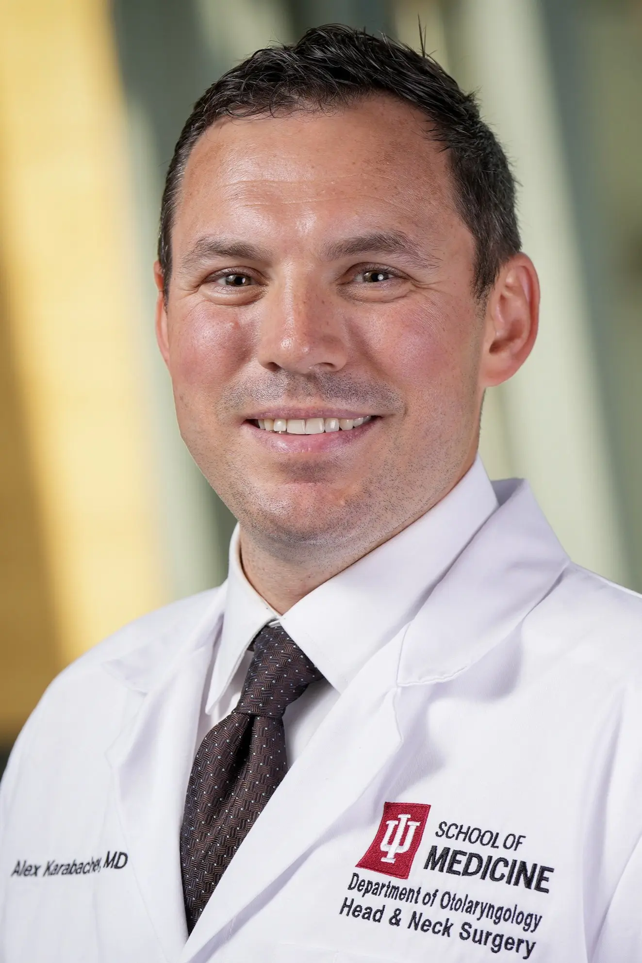 Headshot of a person wearing an IU School of Medicine white coat, standing against a softly blurred indoor background.