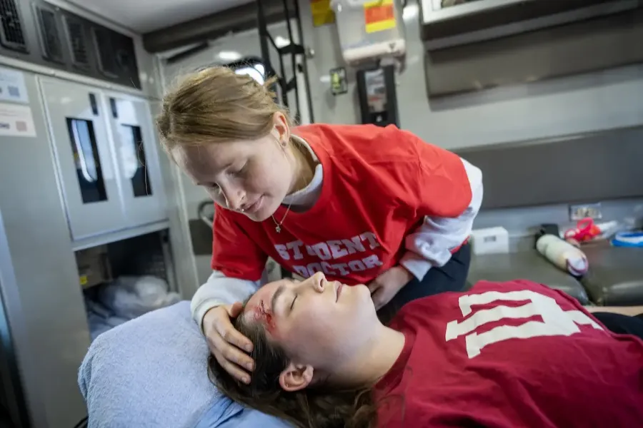 A medical student inspects a head wound of a patient in an ambulance