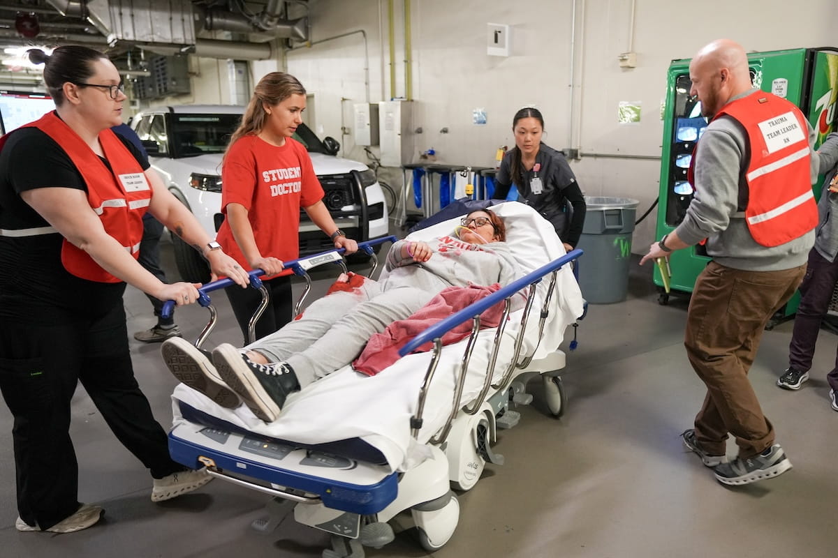 A mock patient is wheeled on a bed by Eskenazi Hospital staff in the ambulance bay