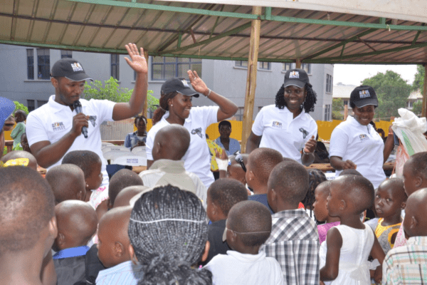 NOHARM study team leaders on a stage celebrating the study with a crowd of young bystanders 