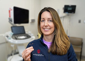 A woman in a blue vest holds an IUD