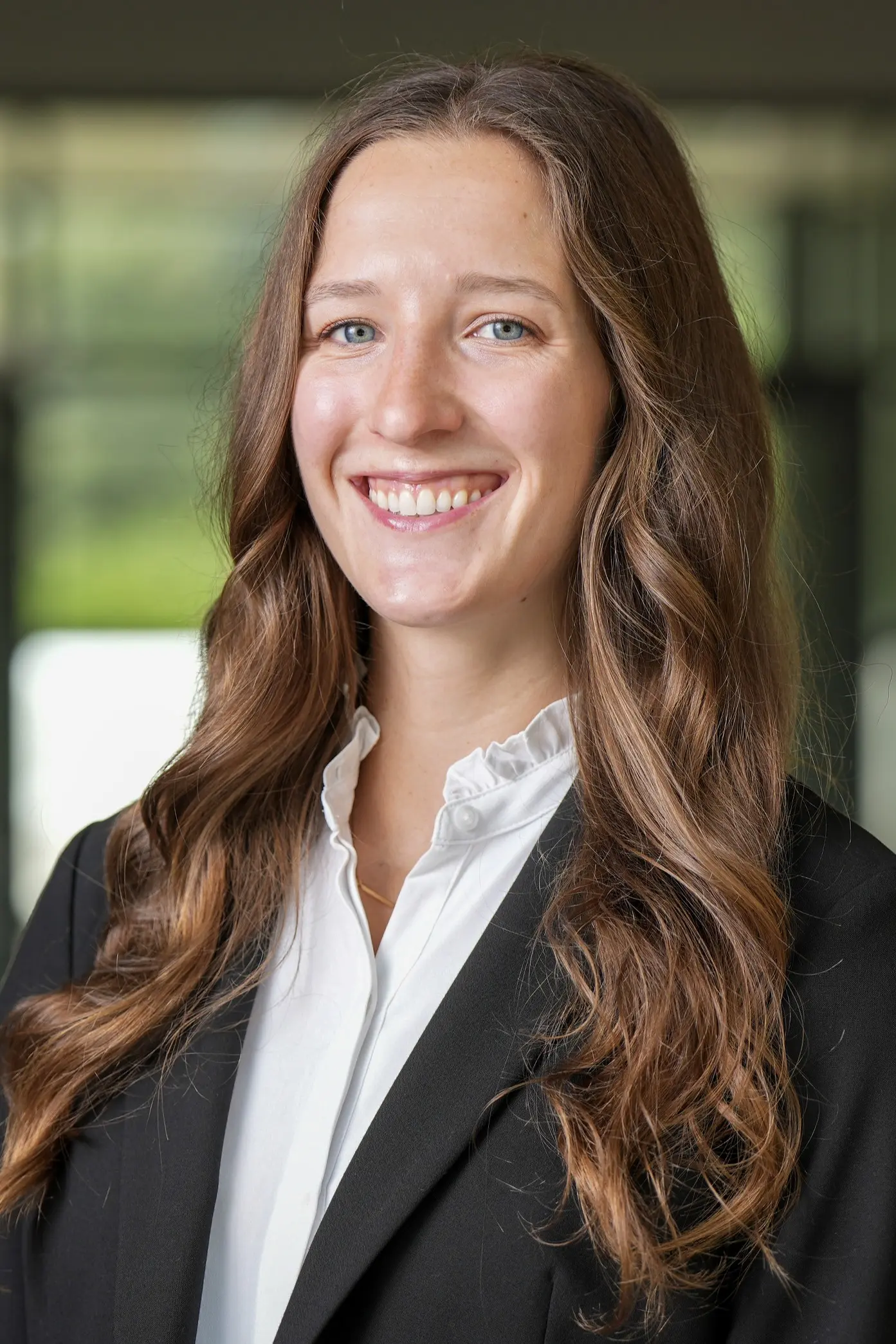 Person in professional attire in front of blurred office lobby background
