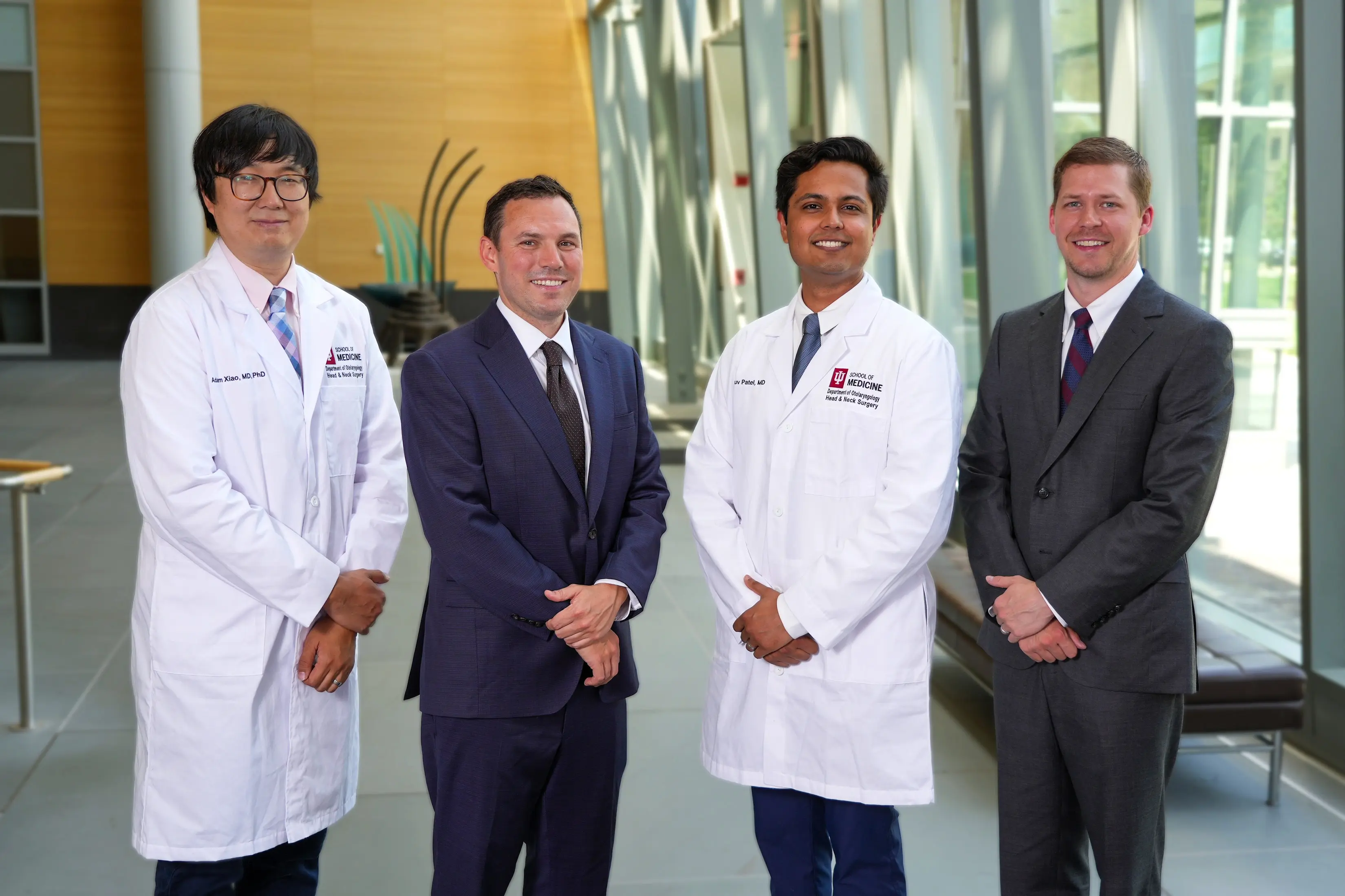Four physicians standing together in lobby with blurred background