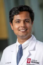 Dhruv Patel | IU School of Medicine Headshot of a person wearing an IU School of Medicine white coat, standing against a softly blurred indoor background.