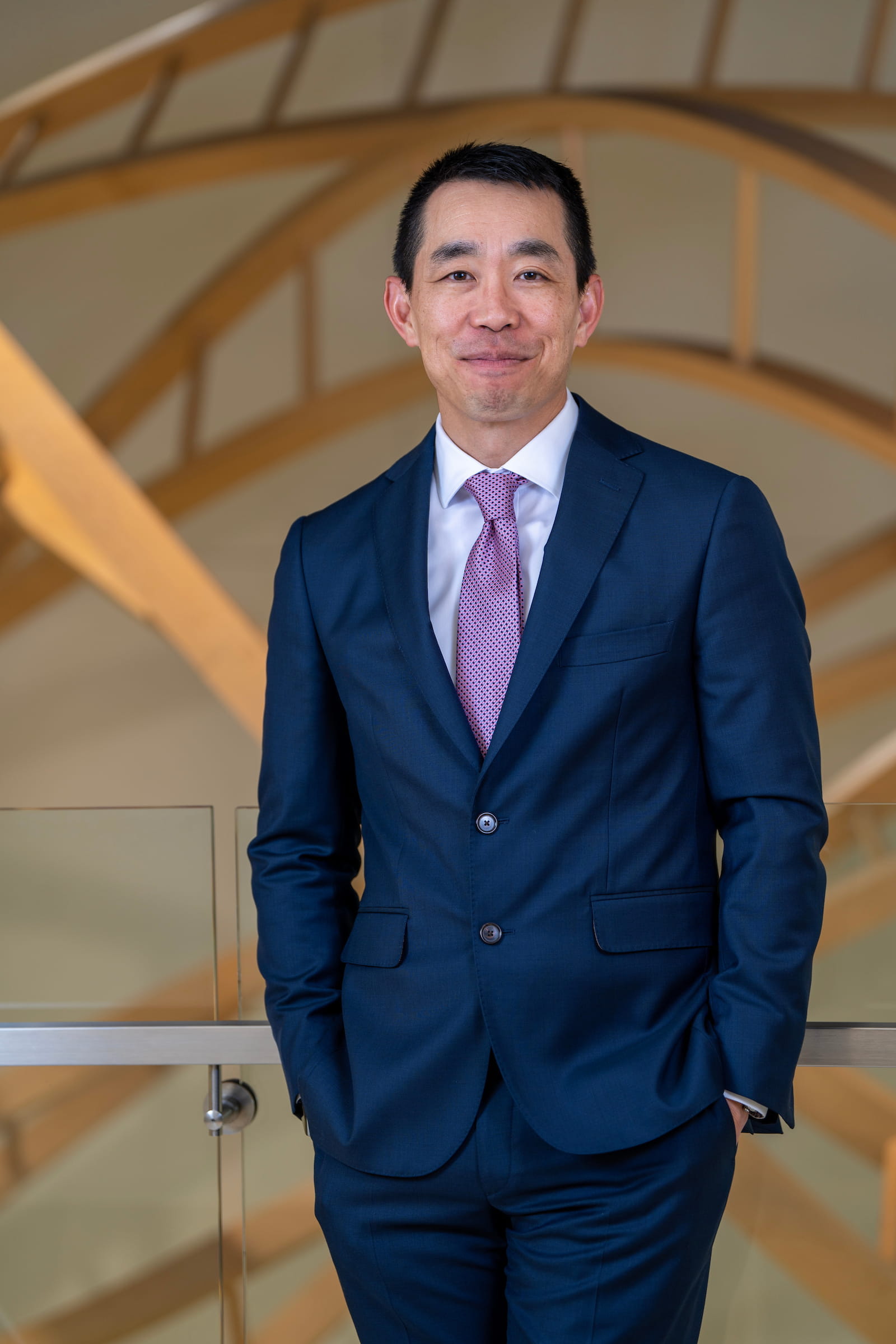 Peter Pang stands with hands in pants pockets, wearing a navy suit