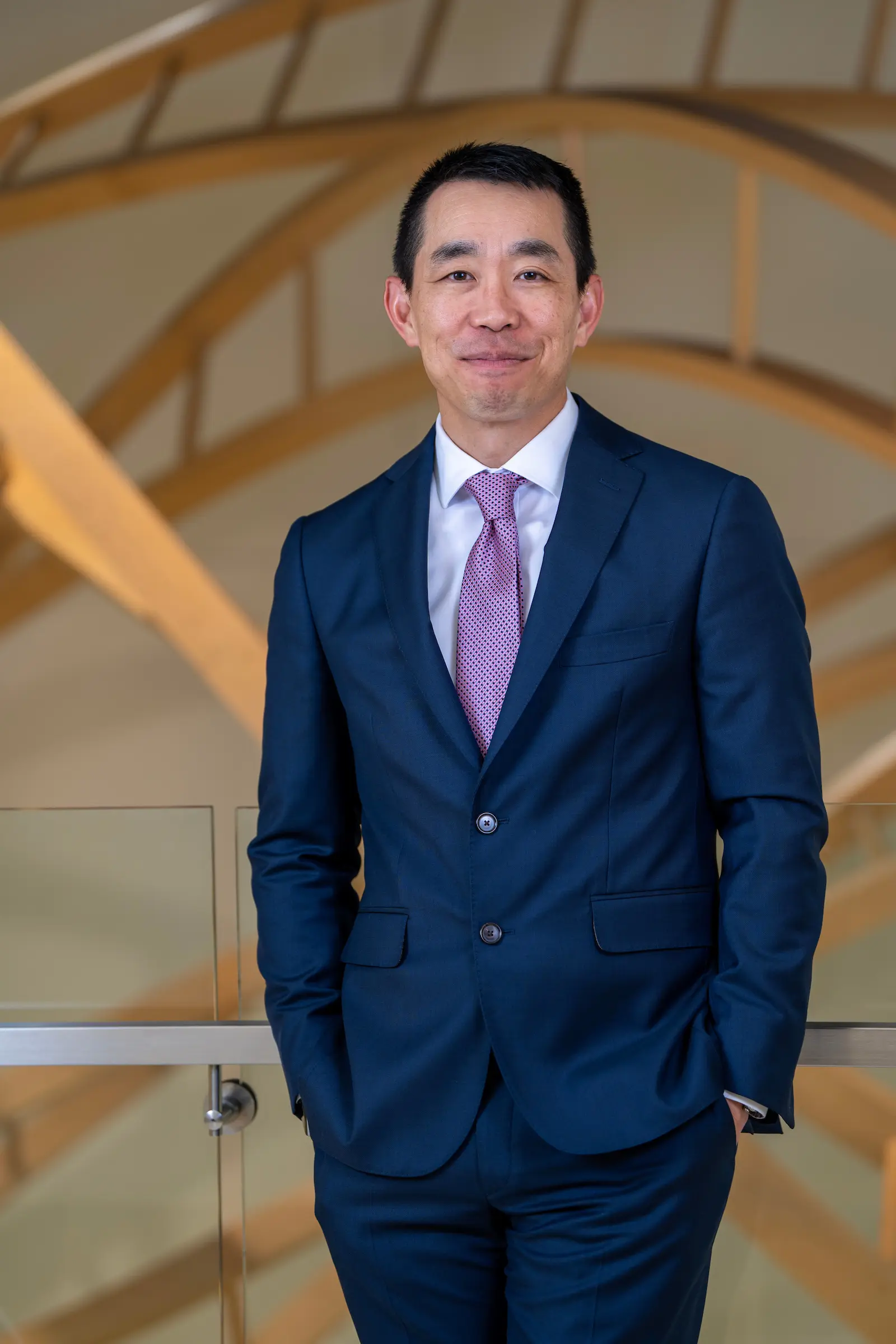 Peter Pang stands with hands in pants pockets, wearing a navy suit