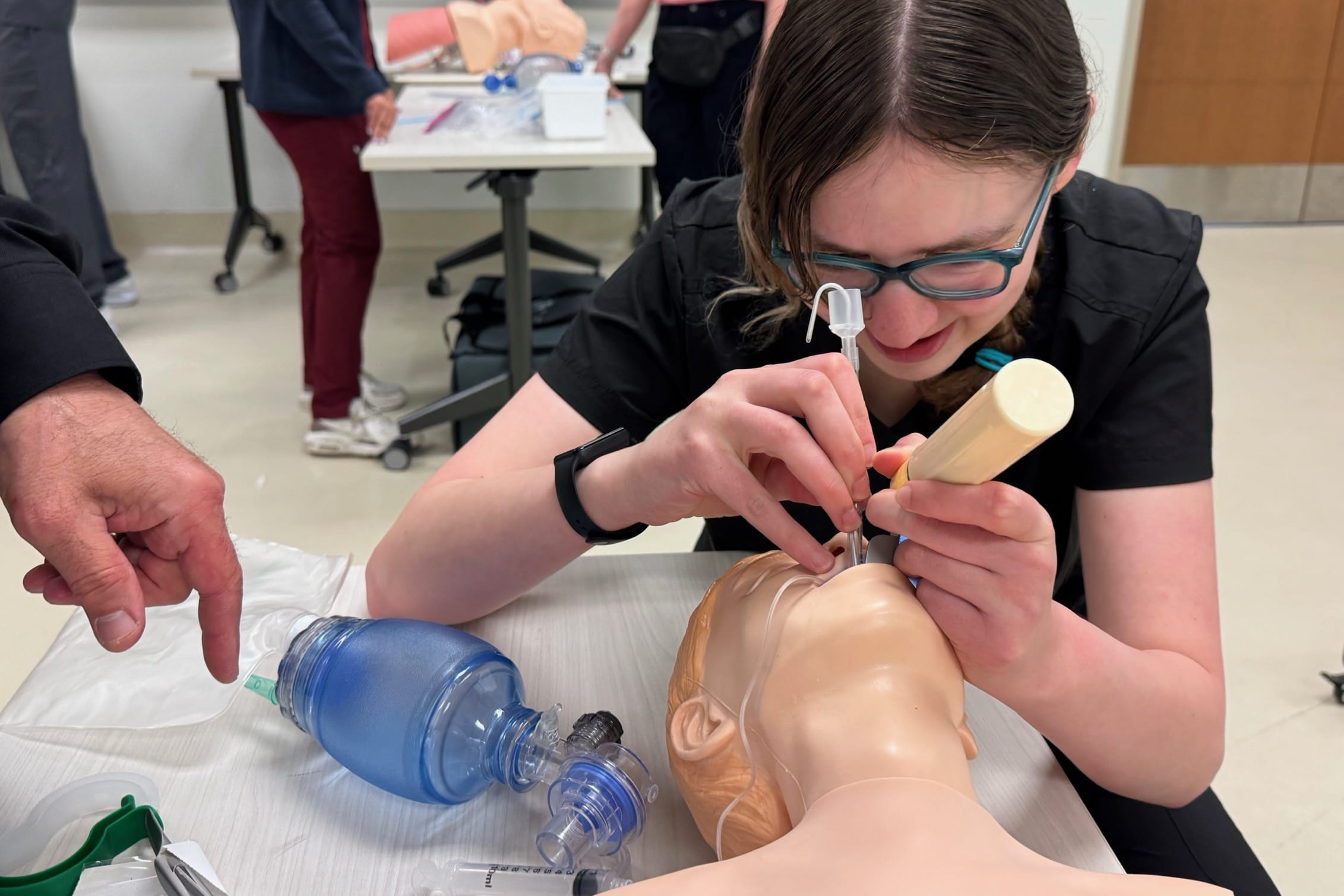 Sarah Vaught uses tools on a manikin to practice opening its airway