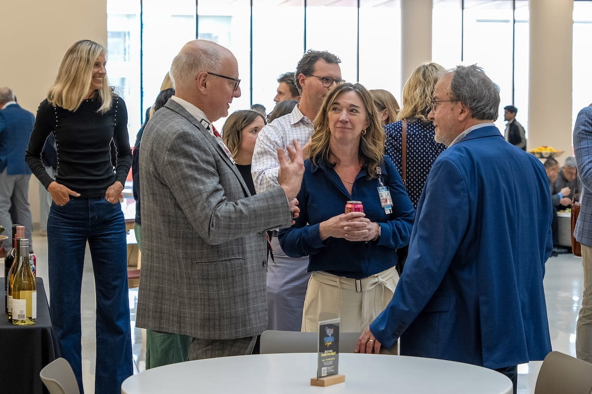 Dean Jay Hess talks with a woman and a man in the lobby of the Medical Education and Research Building.