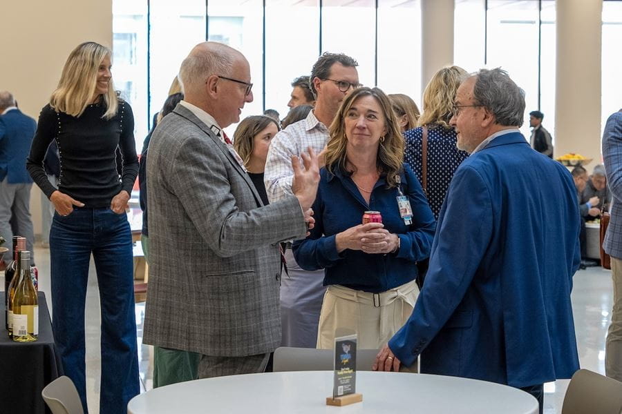 Dean Jay Hess talks with a woman and a man in the lobby of the Medical Education and Research Building.