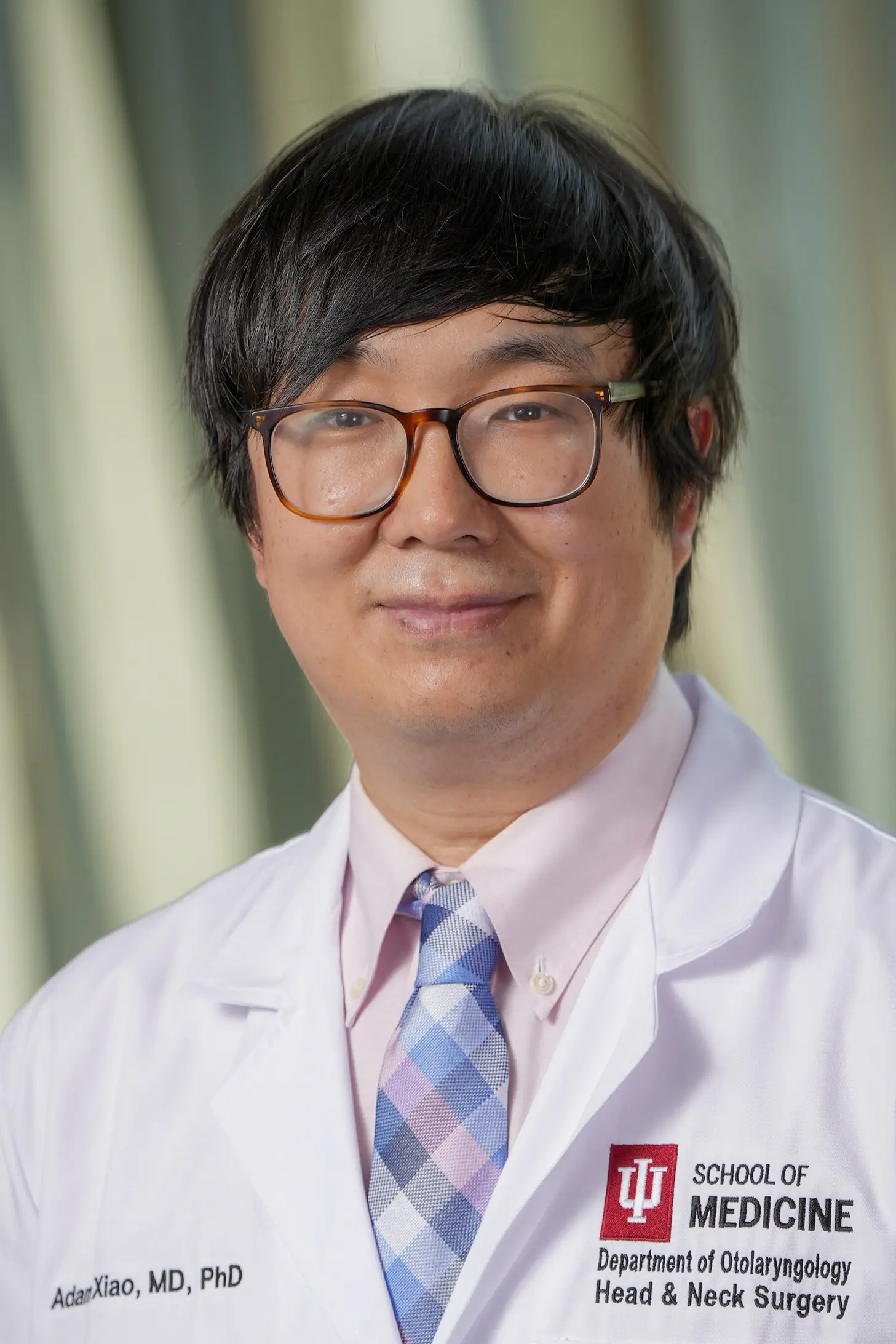 Headshot of a person wearing an IU School of Medicine white coat, standing against a softly blurred indoor background.