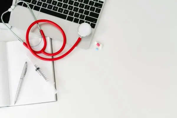 a red stethoscope lays across an open laptop computer