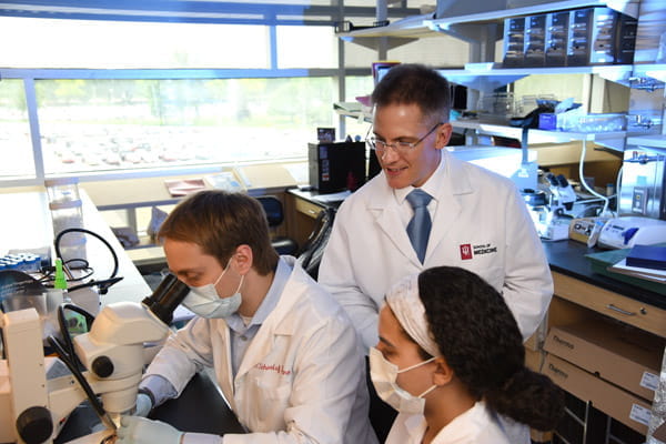 Tim Corson, PhD, works with medical students doing research in the lab.