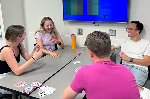 Four IU School of Medicine students play Euchre card game at a table.