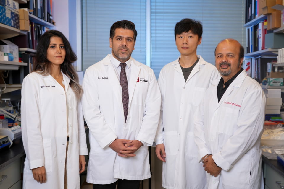 scientists in lab coats standing in lab posing for photo