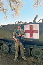 Photo of IU med student Will Hutwagner in uniform in front of a military aid vehicle.